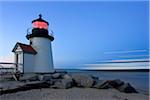 The Brandt Point Lighthouse illuminated at dusk as a ferry passes by, Nantucket, Massachusetts, USA