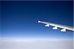 Close-up of the wing of a jet aircraft in flight above the clouds.