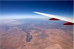 Close-up view an airplane wing from the window of a jet while flying over the Arizona desert, USA