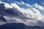 Helicopter in cloudy sky and winter mountains. Ski resort Gudauri. Caucasus Mountains, Georgia.