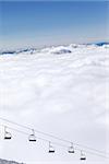 Chair-lift and mountains under clouds in sun day. Caucasus Mountains, Georgia. Ski resort  Gudauri.