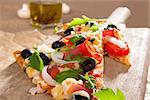 Delicious pizza piece with various toppings close up. Traditional rustic, country style pizza eating background.