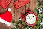 Christmas wooden background with clock, snow fir tree, gift boxes and santa hat