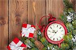 Christmas wooden background with clock, gift boxes, snow fir tree and copy space