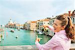 Happy young woman framing with hands while standing on bridge with grand canal view in venice, italy