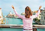 Happy young woman standing on bridge with grand canal view in venice, italy