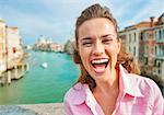 Portrait of happy young woman standing on bridge with grand canal view in venice, italy