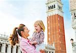 Portrait of smiling mother and baby against campanile di san marco in venice, italy