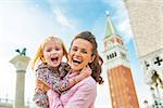 Portrait of happy mother and baby against campanile di san marco in venice, italy