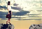 Businesswoman with briefcase standing on the edge of rock gap