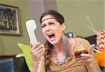 Angry smoker with drink yelling into telephone