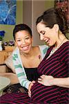 Excited Black woman feeling the belly of pregnant partner