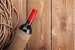 Red wine bottle over rustic wooden table background. View from above with copy space