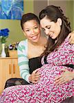 Smiling African woman touching her partner's pregnant belly
