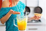 Close-up on fitness young woman making pumpkin smoothie in kitchen