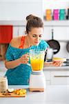 Fitness young woman making pumpkin smoothie in kitchen