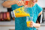 Close-up on fitness young woman pouring pumpkin smoothie in glass