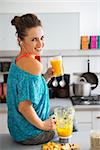 Portrait of happy fitness young woman with glass of pumpkin smoothie in modern kitchen