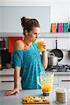 Fitness young woman drinking pumpkin smoothie in kitchen