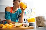 Close-up on fitness young woman drinking pumpkin smoothie in kitchen