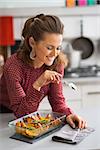 Portrait of happy young housewife with pan of baked pumpkin