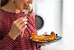 Closeup on young woman eating baked pumpkin in kitchen