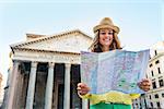 Happy young woman looking at map in front of pantheon in rome, italy