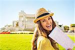 Portrait of smiling young woman with map on piazza venezia in rome, italy