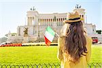 Young woman with italian flag on piazza venezia in rome, italy. rear view