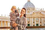 Happy mother and baby girl with photo camera on piazza san pietro in vatican city state