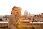 Mother and baby girl on street overlooking rooftops of rome on sunset
