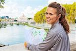 Portrait of smiling young woman with map on bridge ponte umberto I with view on basilica di san pietro