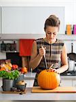 Young housewife pumpkin in kitchen