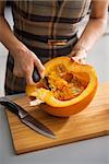 Closeup on young housewife removing filling from pumpkin