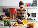 Young housewife cutting pumpkin in kitchen