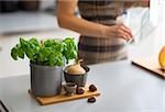 Closeup on fresh basil on table and housewife in background