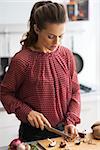 Young housewife cutting mushrooms in kitchen