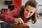 Happy young housewife decorating freshly baked pumpkin bread with seeds