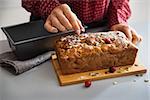 Closeup on young housewife decorating freshly baked pumpkin bread with seeds