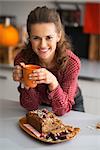 Happy young housewife drinking tea with freshly baked pumpkin bread with seeds