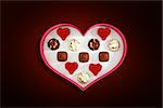 Heart shaped box of candy against red background with vignette