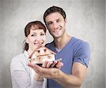 Couple holding a model house against weathered surface