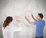 Couple deciding to hang picture against weathered surface