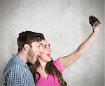 Couple taking selfie with digital camera against weathered surface
