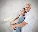 Happy couple hugging and holding paint roller against weathered surface