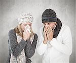 Sick couple in winter fashion sneezing against weathered surface