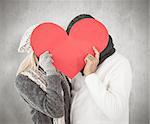 Couple in winter fashion posing with heart shape against weathered surface