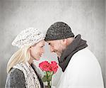 Smiling couple in winter fashion posing with roses against weathered surface