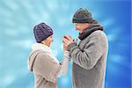 Happy mature couple in winter clothes embracing against valentines heart design