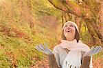 Brunette in warm clothing against peaceful autumn scene in forest